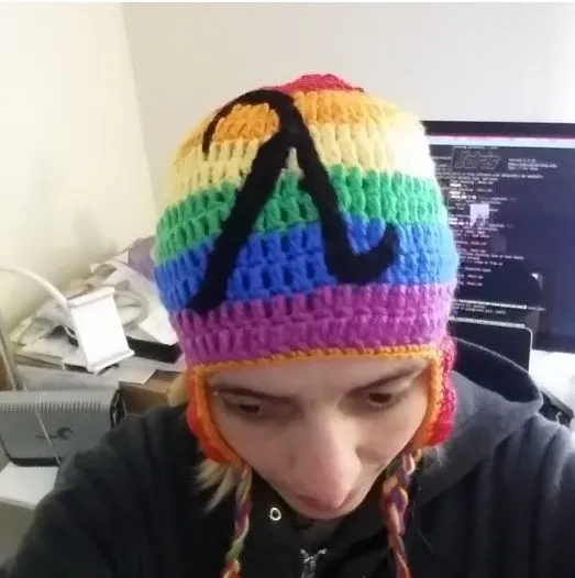 Photo of Susan wearing a lambda knit rainbow hat